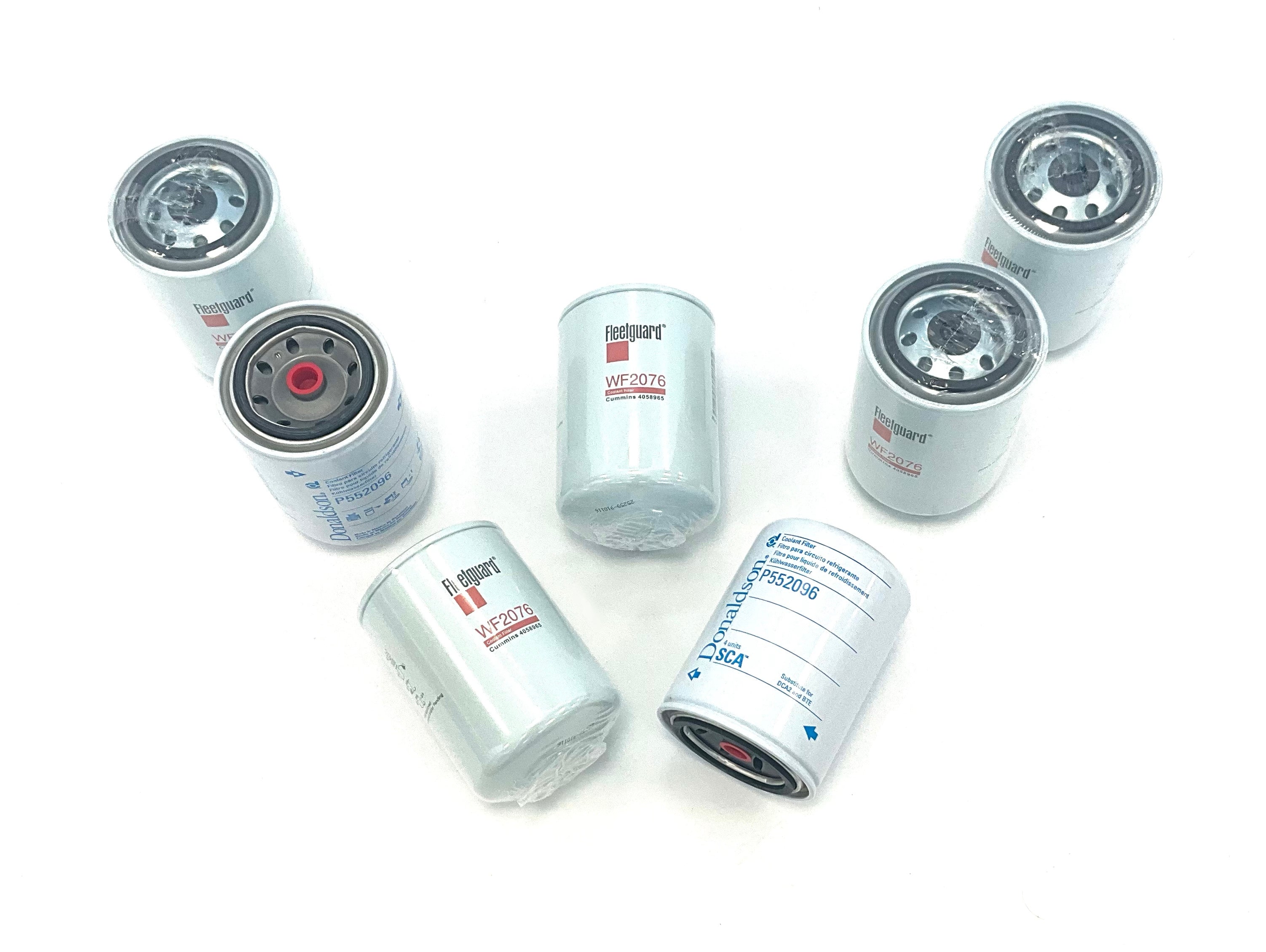 Seven cylindrical heavy duty water filters in various orientations, showing white bodies with grey metal ends and some printed specifications, arranged on a plain white background, arrange to spell the letter 'W'.